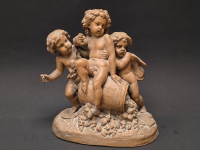 une statue représentant trois chérubins assis sur un tonneau