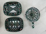four pieces of green and red pottery sitting on a white surface