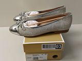 Il s'agit de deux paires de chaussures argentées posées sur une boîte.