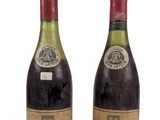 two bottles of wine sit next to each other on a white surface