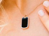 the woman is wearing a necklace with a black stone on it