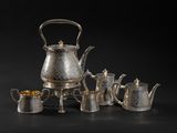 a group of silver tea and coffee pots on a black background