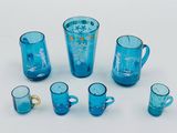 a group of blue glass cups and mugs on a white surface