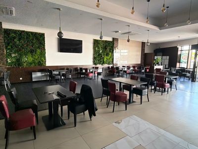 de nombreuses tables et chaises dans un restaurant où une télévision est accrochée au mur