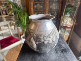 a silver vase sitting on top of a wooden table