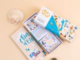 a book and a bookmark sitting on a table next to some seashells