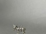 a small silver figurine of a cow on a table