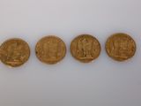 quatre pièces d'or sont disposées en ligne sur une surface blanche