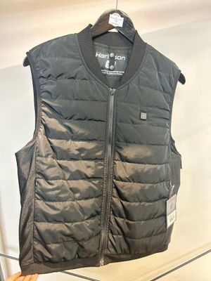 un gilet noir accroché à un cintre dans une pièce