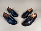 three pairs of black leather shoes on a white surface