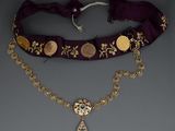 a close up of a necklace with a coin on a chain