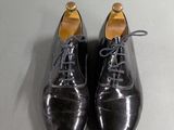 pair of black leather shoes with laces on a grey surface