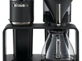 La cafetière est posée sur un support sur lequel se trouvent deux tasses.