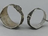 pair of silver bracelets with intricate designs on them on a gray surface