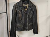 une veste en cuir noir accrochée à un porte-vêtements dans une pièce