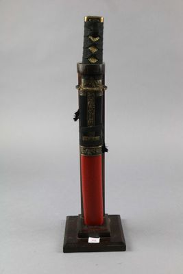 a black and red pen sitting on top of a wooden stand