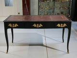 une table noire ornée de détails dorés, avec une vitrine en arrière-plan