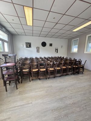 des tables et des chaises dans une pièce où est accrochée une horloge au mur
