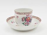 a white cup and saucer with a pink flower design on it