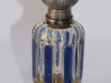 a small silver and blue glass bottle on a white surface
