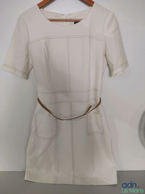 the white dress is hanging on a hanger on the wall