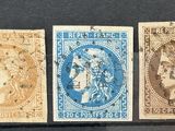 Quatre timbres de couleurs différentes sont exposés dans une vitrine.