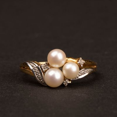 gros plan d'une bague en or avec des perles et des diamants