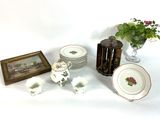 a table with a vase of flowers, plates, and a vase of flowers