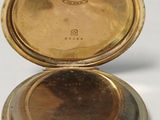 an image of a gold pocket watch sitting on top of a white table