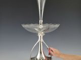 a person reaching for a silver vase on a stand