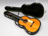 une guitare dans un étui, posée sur une surface blanche