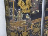 two black and gold painted panels with figures on them