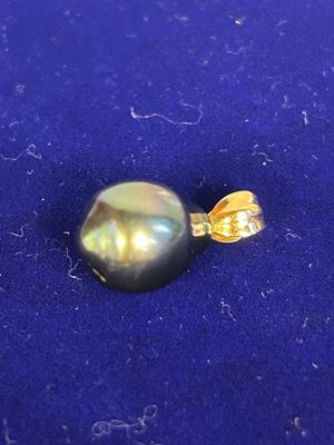 a black pearl on a blue cloth with a gold bead
