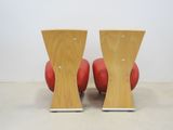 two red chairs with wooden legs sitting on top of each other