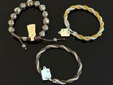 three bracelets with silver beads and a tag on a black surface