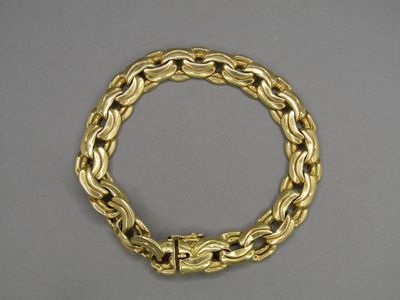 a close up of a gold bracelet on a gray surface