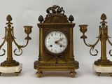 trois bougies et une horloge posées sur une table
