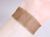 someone is wearing a bracelet that has a mesh design on it