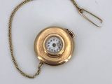 an image of a gold pocket watch with a chain on a white surface