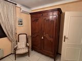 a room with a bed, chair, and armoire in it