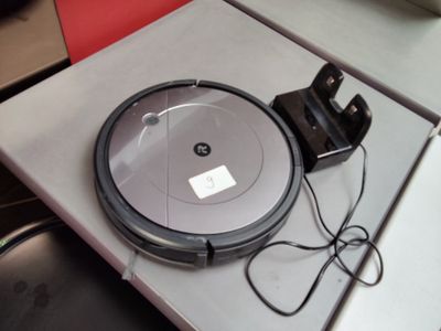 un robot aspirateur posé sur une table, avec un chargeur posé dessus