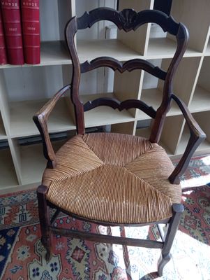 une chaise en bois avec une assise tressée, placée devant une bibliothèque