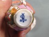 a hand holding a small vase with a monogram on it