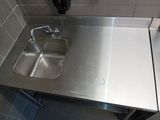 a stainless steel sink in the corner of a bathroom