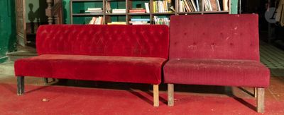 un canapé rouge placé devant une bibliothèque dans une pièce