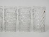 four clear glass tumbles with designs on them sitting on a white surface