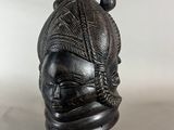 a black sculpture of a woman ' s head on a stand