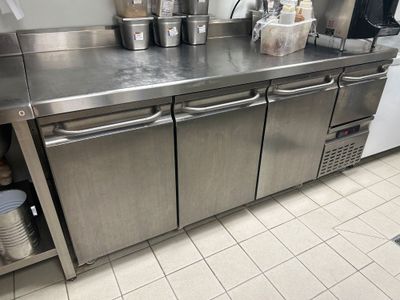 un plan de travail en inox sur lequel sont posés tout un tas de casseroles et de poêles