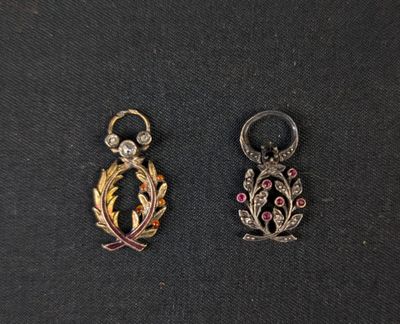 two small gold and silver charms on a black surface