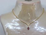 gold chain necklace with a garnett on a mannequin torso